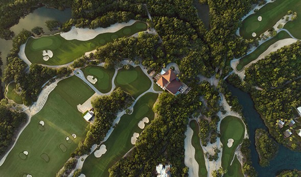 Vista de drone del diseño del campo de golf El Camaleón Mayakoba, mostrando fairways entre selva densa y trampas de arena blanca en Riviera Maya.