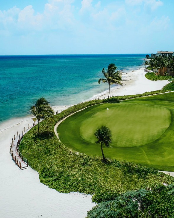Hoyo exclusivo del campo de golf El Camaleón Mayakoba con bandera en el green, arena blanca y vistas al Mar Caribe en la Riviera Maya.